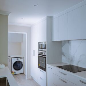 ZYR01052-HDR Sleek modern galley kitchen that leads to a laundry area with washer, dryer, and cabinet storage.